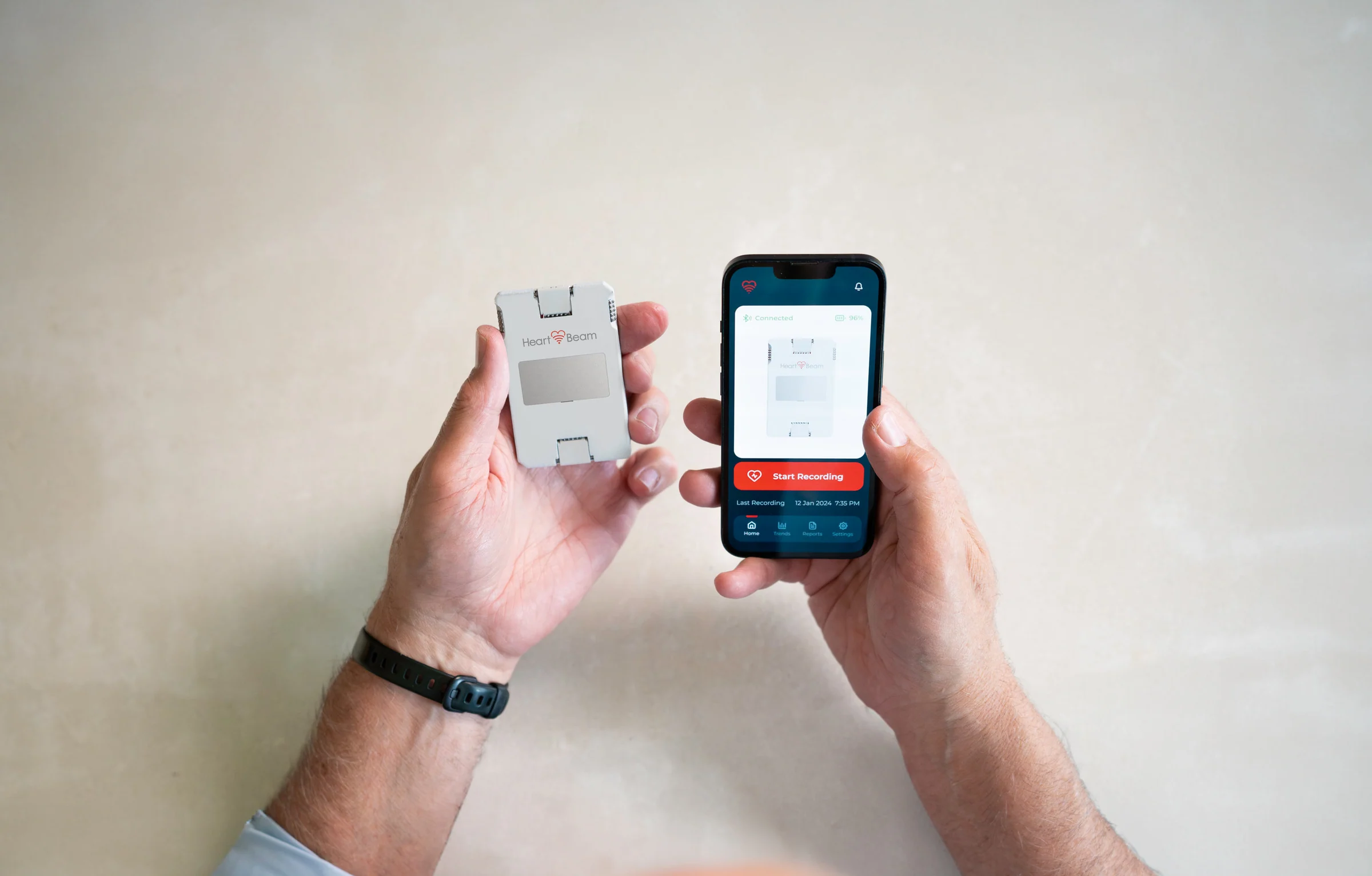 Hands holding the HeartBeam recorder and the patient app