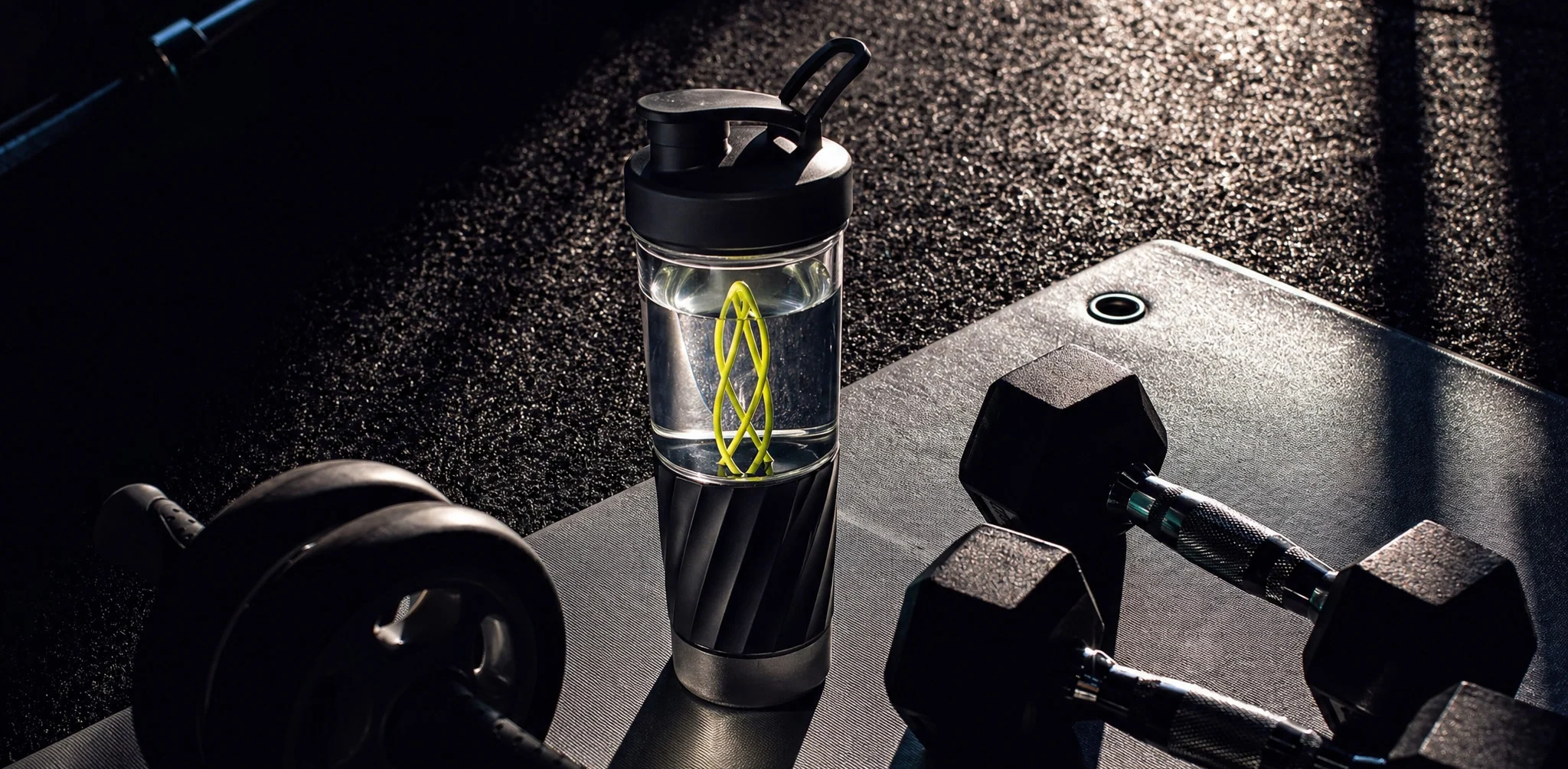 Volvi shaker on a gym floor beside dumbbells